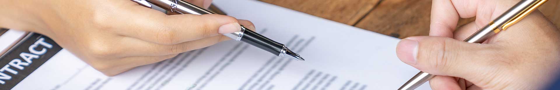 Real estate documents laid out on a desk with a pen and digital signing device.